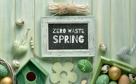 Easter flat lay on light green wooden planks with springtime decorations, eggs, nesting box and...