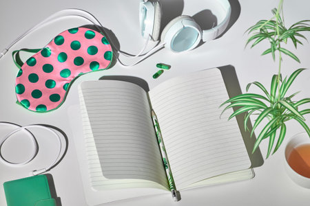 Healthy night sleep creative concept in pink and green. Sleep mask, earphones, tea, sleeping pills,...