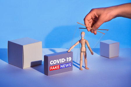 Covid19 novel coronavirus rumors. Sinister hand control wooden puppet on abstract geometric...