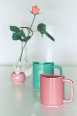 Pink rose flower, twin half tea mugs in pink and fresh mint or Biscay green. Minimalist design for your house in pastel colors. Modern interior decor, romantic gifts. Greeting card for Valentine day.の写真素材