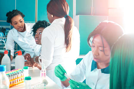 Female African medical students, young graduates in research, medical test lab performing various testing on samples. Nucleic acid pcr test to detect novel coronavirus, new blood test for antibodies.の写真素材