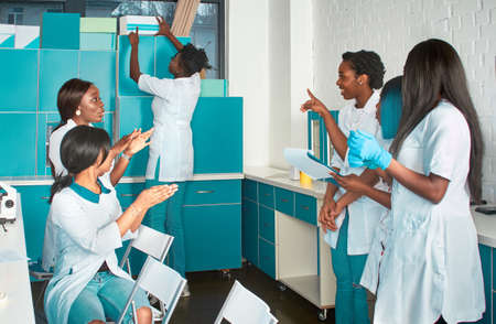 Female African medical students, young graduates or doctors discuss ongoing project. Energetic expressive group discussion in research facility. Testing samples from patients with Covid-19 disease.の写真素材
