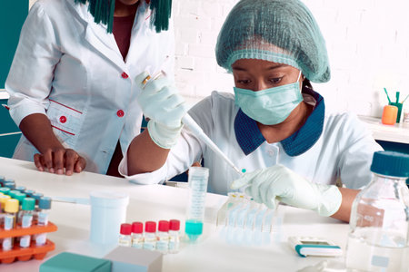 PCR test for coronavirus. African young female tech, scientist or medic in white coat and hat...