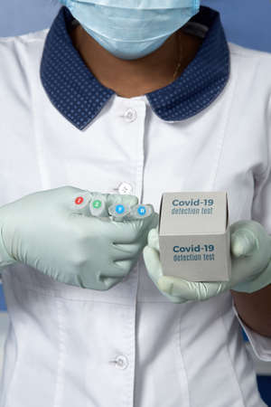 Testing system for detection of nucleic acids, rna, dna for novel coronavirus SARS-CoV-2 in patients for Covid-19 diagnosis. Medic or tech in white gown , mask and gloves holding reagentsの写真素材