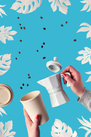 Zero waste coffee background with exotic paper leaves, monstera, fig leaf on blue mint background. Hands hold ceramic espresso coffee maker and eco friendly reusable bamboo zero waste coffee cup.の写真素材
