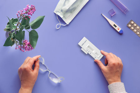 Face mask, thermometer and pills, neon purple background. Rapid COVID-19 test for detection of...