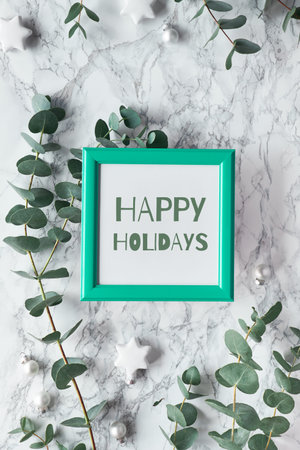 Christmas, New Year winter frame with fresh eucalyptus twigs and white black trinkets, baubles with...