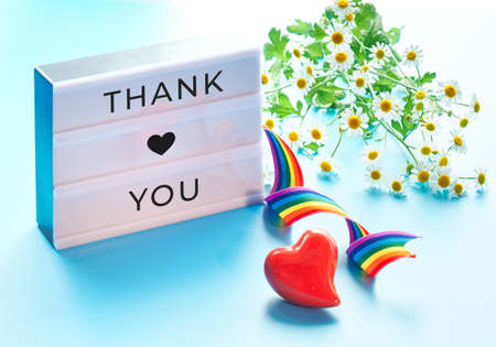 Lightbox with text "Thank you", camomile flowers. Heart, rainbow ribbon, symbols of public support for doctors, nurses, medical stuff fight Covid-19 pneumonia across the globe in many countries.の写真素材
