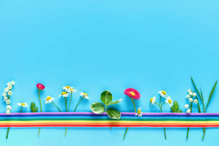Creative flat lay on blue mint background with copy-space. Thank you doctors and nurses! Rainbow ribbon covering various Spring flowers, primrose, chamomile, lily of the valley.の写真素材