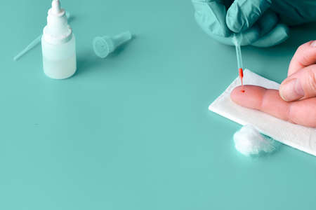 Express COVID-19 test for IgM and IgG antibodies to novel coronavirus SARS-CoV-2, Covid-19. Nurse hand in nitril glove collects patient blood with pipette. Gren mint turquoise background, copy-space.の写真素材