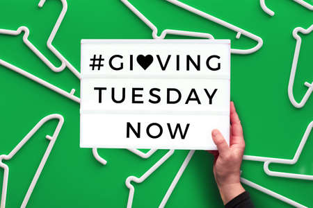 Creative Giving Tuesday concept. Geometric paper flat layout with paper stripe heart in hand with empty hangers. Givingtuesday is campaign for sustainable lifestyle against uncontrolled consumption.の写真素材