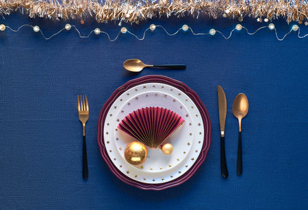 Christmas table setting in gold, burgundy and dark blue colors. Flat lay, top view on decorative...