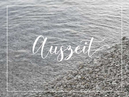 Pebble stones by the sea, diagonal water edge. Tranquil natural background. Text here is in German means time-out.の写真素材