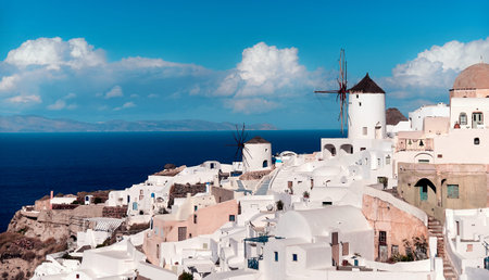 Clouds fly over Oia village on Santorini island in Greece. Traditional white houses and historic...