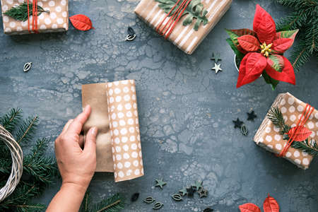 DIY Christmas gifts and handmade decorations. Natural plastic free eco-friendly Xmas celebration. Craft wrapping paper in hands. Flat lay, top view on grey background.の写真素材