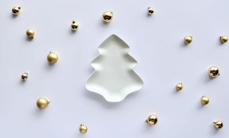 Various Xmas baubles around fir shaped plate on white paper. Trendy minimal flat design for Xmas...