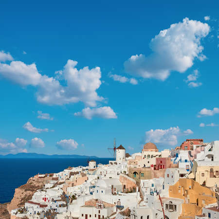 Windmills in Oia village, Santorini island, Greece on a bright day with clouds in blue sky.の写真素材