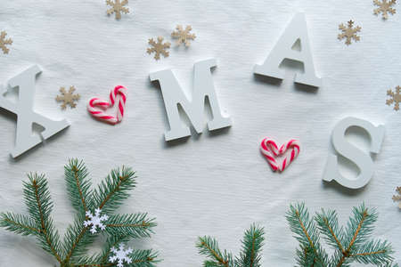 Creative Christmas flat lay with large white letters Xmas on white textile. Eco friendly craft paper decorations, fir twigs and candy cane hearts.の写真素材