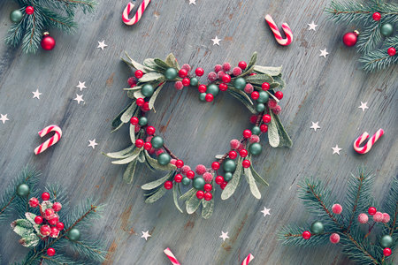 Decorative mistletoe wreath in shape of heart. Wooden Christmas background decorated with natural...