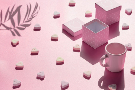Abstract holiday background in pink. Geometric arrangemet with gift boxes, sugar heart candy and...
