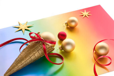 Christmas decorations in LGBTQ community rainbow flag colors. Ice cream waffle cone, golden baubles...