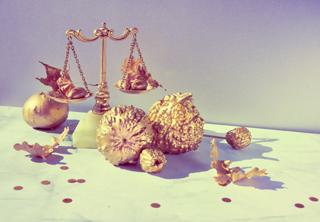 Autumn arrangement. Retro decorative weight balance, gold pumpkins and leaves on marble.
