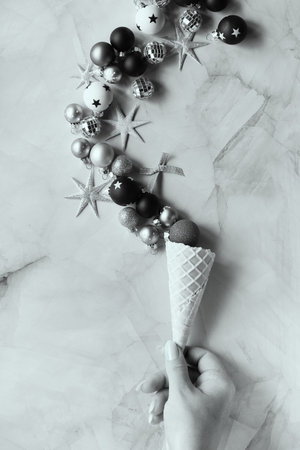 Creative Christmas or New Year black and white flat lay. Hand with ice cream cone and Xmas...