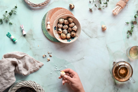 Quail Easter eggs and natural Spring decorations and eucalyptus twigs on marble.