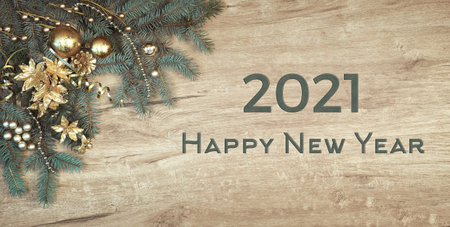 Christmas background on wood with a corner of decorated fir tree branches. Text Happy New Year 2021.