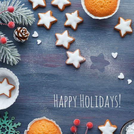 Christmas background with star cookies, tasty lemon muffins, winter decor. Text Happy Holidays.の写真素材