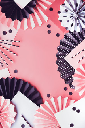 Abstract background on layered paper. Folded paper fans and confetti on black, pink and white.