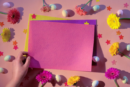Easter creative flat lay. Marzipan Easter eggs, gerbera daisy flowers and floral confetti on cream...