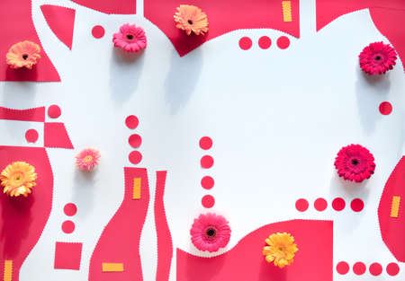 Organic paper shapes with gerbra flowers. Abstract geometric background in pink and orange on white. Vibrant flat lay with arrangement of flowers, polka dots and various shapes.の写真素材