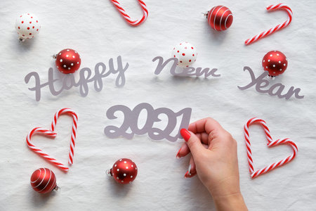 Happy New Year 2021 text. Flat lay with female hands holding paper number 2021. Christmas...