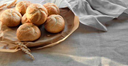 Crusty round buns, Kaiser or Vienna rolls. Buns are on baking paper on table with linen table cloth.の写真素材