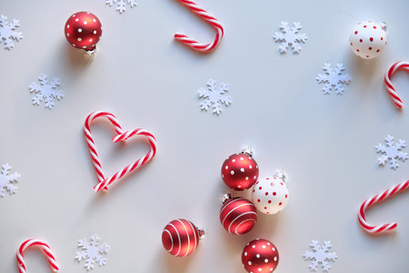 Panoramic Christmas background, top view with female hand holding heart shape made from candy canes....