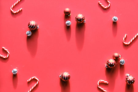 Christmas simple arrangement on red background with shadows. Flat lay with Xmas decorations - candy...