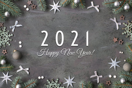 Happy New Year 2021 text. Flat lay background in silver, grey and green. Top view with fir twigs...
