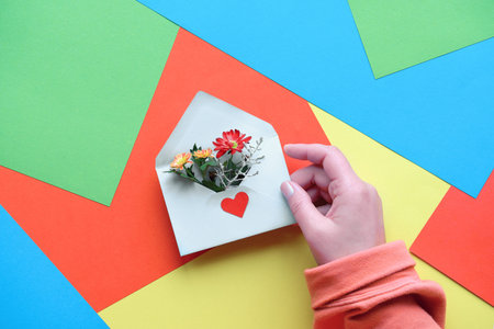 International Thank you day. Greeting card with female hand holding envelope with heart shape and...