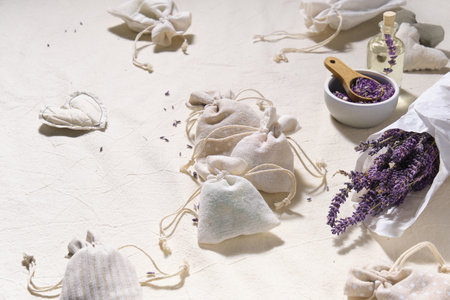 Hand made lavender sachets in small bags and cotton hearts on textile tablecloth. Dry lavender flowers in tracing paper and jar. Glass bottle with lavender oil. Natural homemade gifts.の写真素材