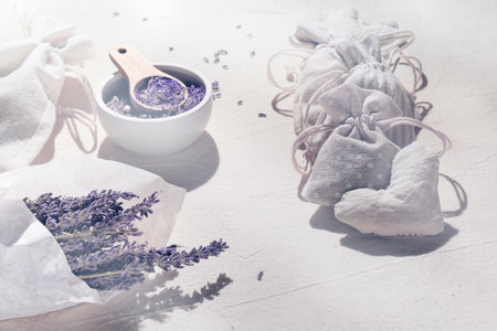 Hand made lavender sachets in textile bags and soft cotton hearts. Dry lavender flowers in tracing paper. Jar and scoop with dry flowers, burning lavender scented candle. Homemade fragrance, flare.の写真素材