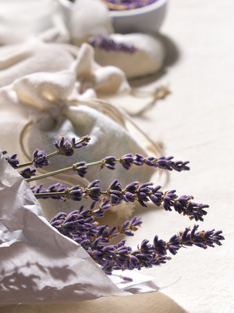 Hand made lavender sachets in textile bags and cotton hearts on cotton background. Low impact natural lifestyle. Bunch of dry lavender, close-up. Dry lavender flowers in wrapping paper.の写真素材