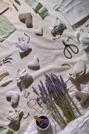 Hand made lavender sachets in textile bags, soft hearts. Hand hold sachet. Dry lavender flowers for stuffing. View from above, flat lay, textile tablecloth. Zero waste, low impact lifestyle.の写真素材