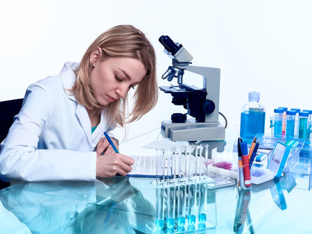 Pink tulips on mint blue color cotton sweater, blank greeting card in pink envelope. Coffee cup with heart as latte art. Plate of pink marshmallows. Flat lay on blue paper, copy-space.の写真素材