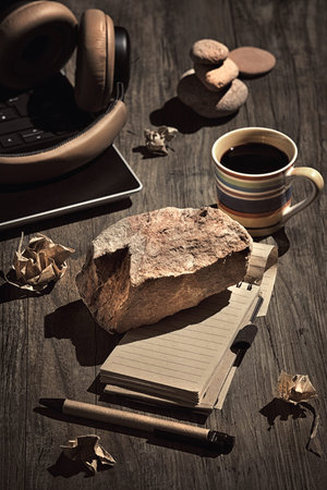 Writers Block. Concept still life, arrangement on dark wooden table. Heavy stone, brick on open...