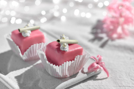 Valentine petit fours with marzipan icing. Fragrant pink hyacinth flower. Garland of lights on white...