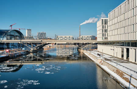 BERLIN, GERMANY - FEBRUARY 14, 2021: Berlin main railway station Hauptbahnhof, Hbf. Panorama over Spree river with reflection. Snow on riverside, ice on the river. Modern architecture in Germany.のeditorial素材