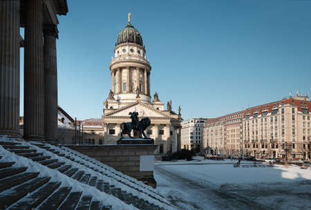 Gendarmenmarkt square in Berlin with French Cathedral, or Franzusischer Dom in German. Picture taken from the steps of Concert Hall on a bright Winter day with blue sky and snow.の写真素材