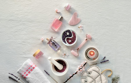 Crystal rose quartz facial roller, Gua sha stone for face massage. Flat lay on off white textile....