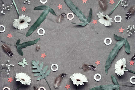 Jungle floral flat lay on linen textile. Bold tropical plant mix with copy-space. White gerbera flowers, feathers, quail eggs. Springtime floral top view, natural colors, exotic fern leaves.の写真素材